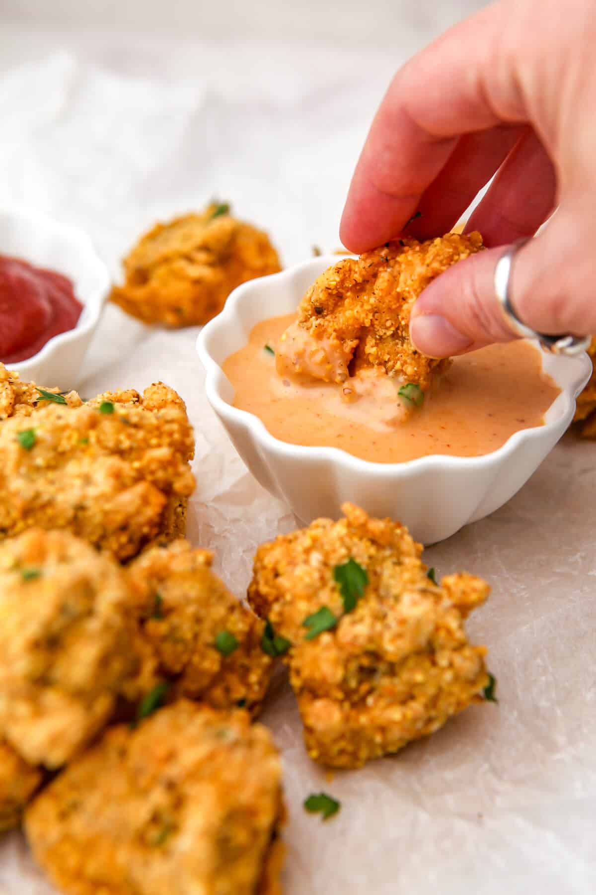 A vegan nugget being dunked in a small bowl of vegan chick fil a sauce.