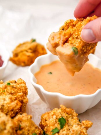 A tofu nugget being dipped into vegan chick fil a sauce in a small white bowl.