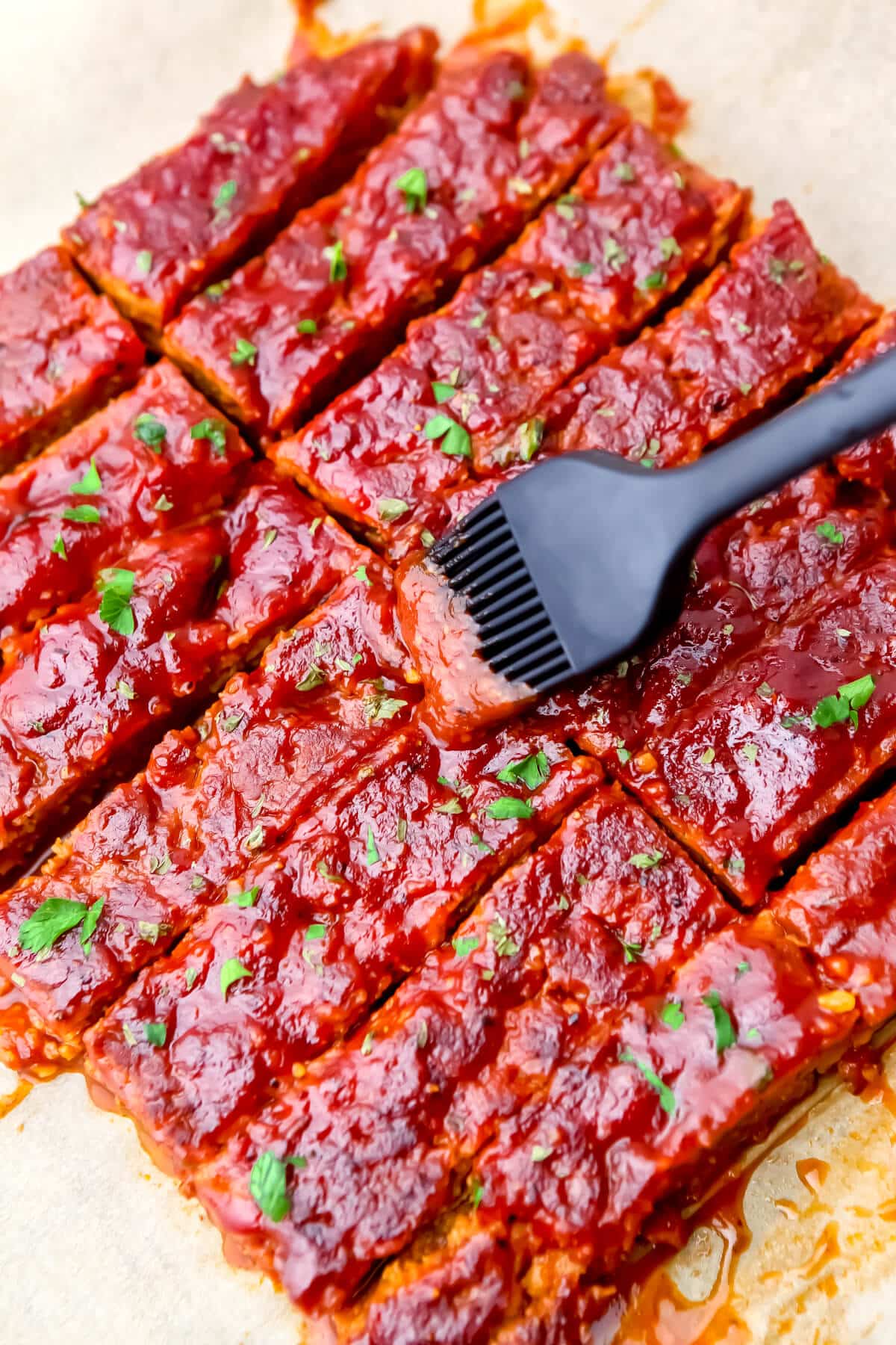 Seitan ribs being brushed with BBQ sauce.