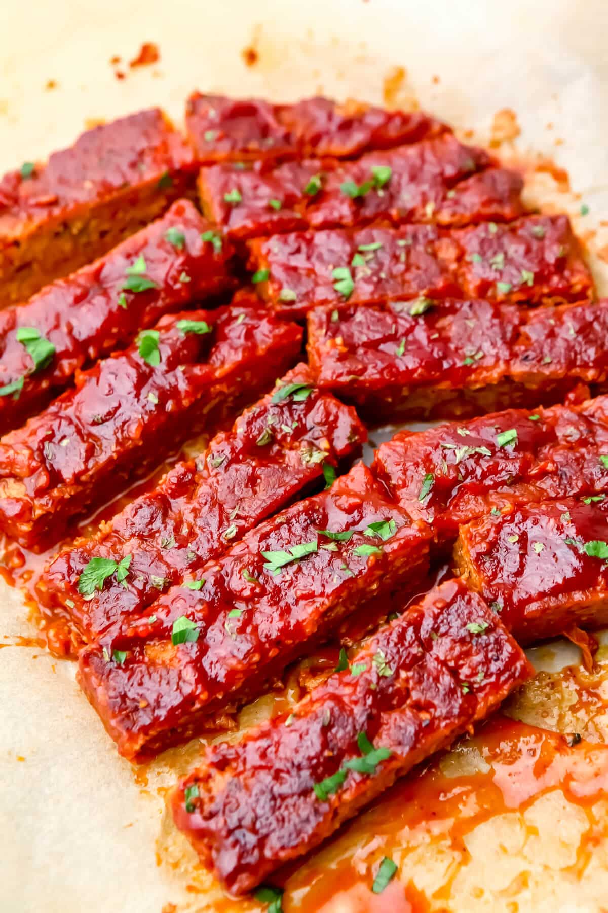 Vegan ribs made from seitan with BBQ sauce on them and sprinkled with parsley.