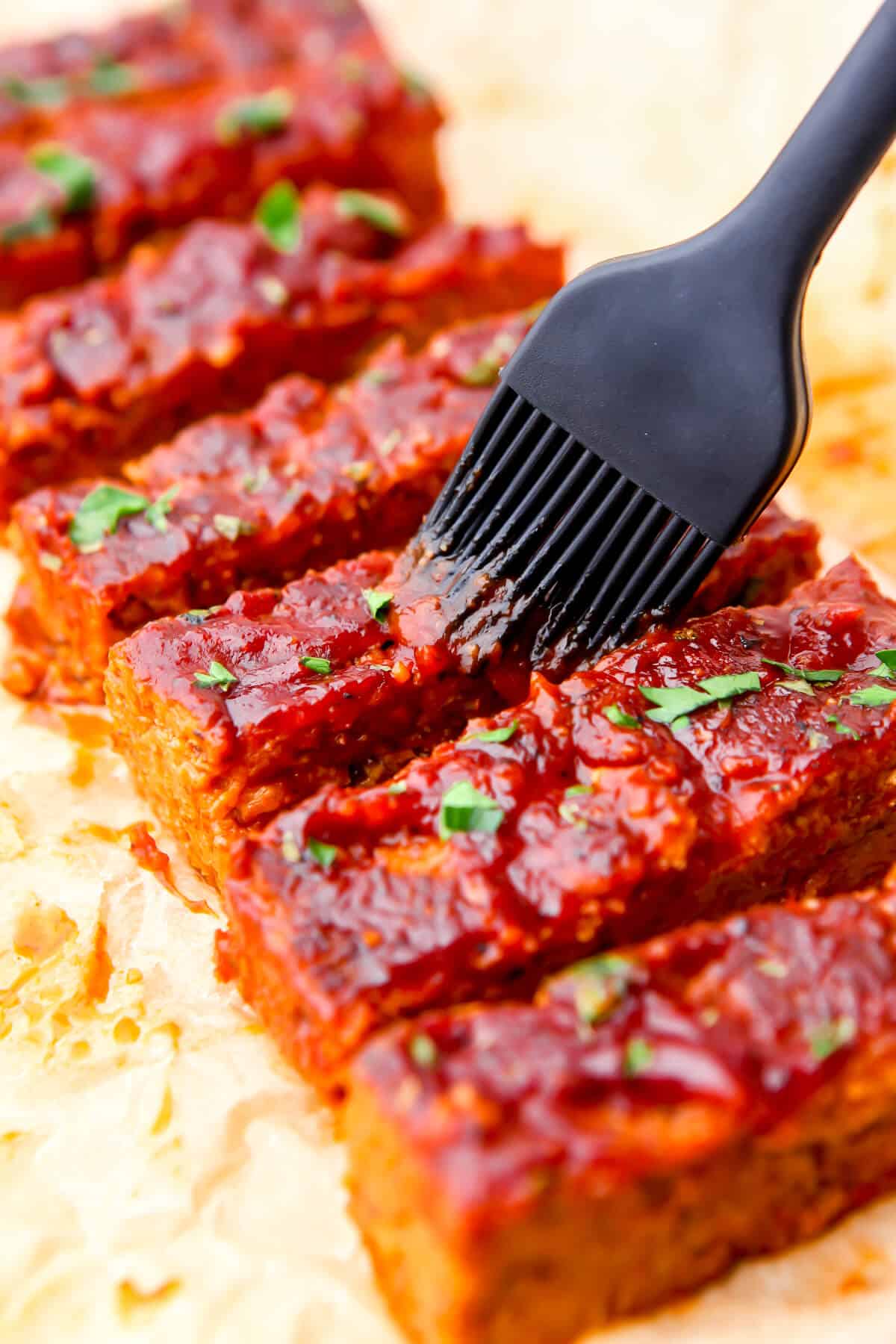 Vegan ribs being brushed with BBQ sauce.
