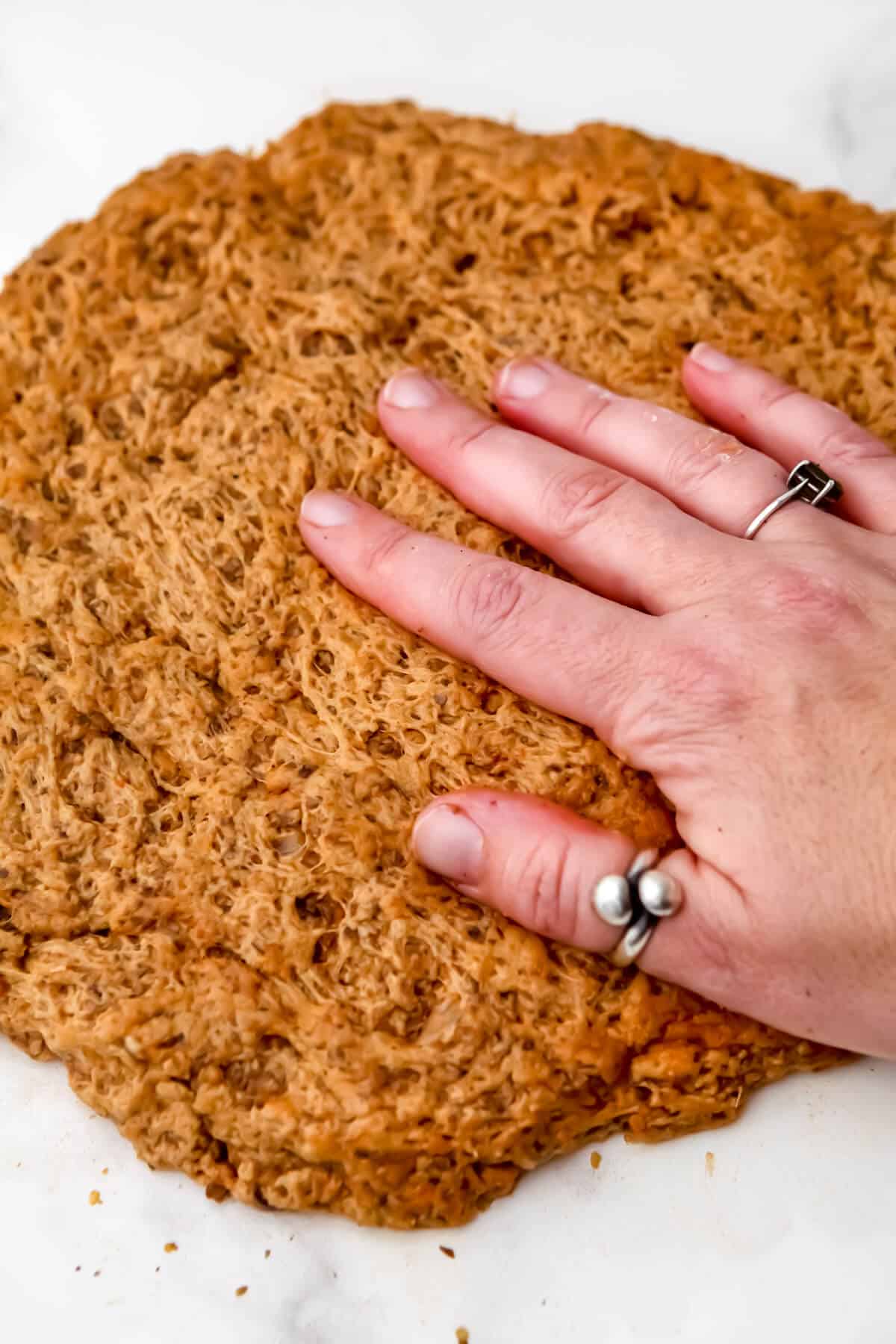 A large flattened round piece of seitan dough before it has been cooked.