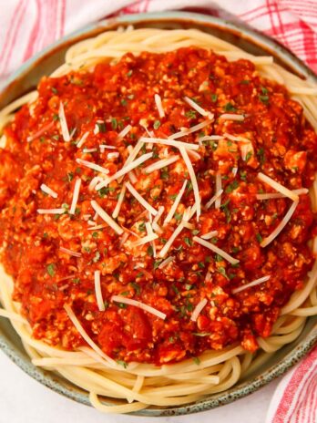 A plate of spaghetti topped with tofu Bolognese with a fork on the side.