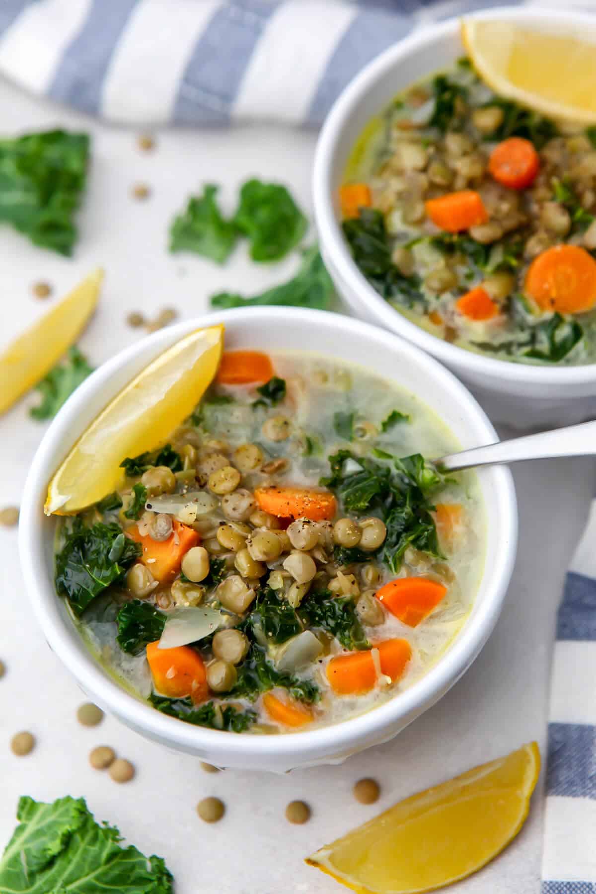 A top view of 2 bowls of lentil soup with carrots, kale, and lemon in a creamy sour cream broth.