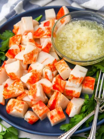Vegan lobster pieces on a blue plate with melted vegan butter on the side for dipping.