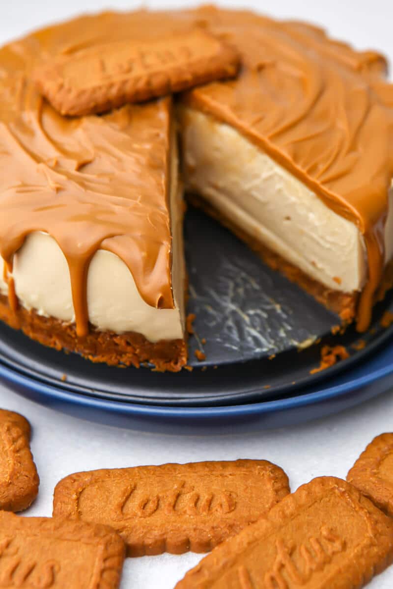 A vegan Lotus Biscoff Cheesecake with a slice cut out of it.
