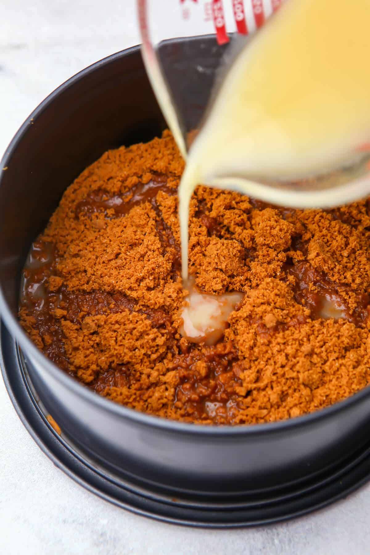 Biscoff cookie crumbs with melted butter being added to make a crumb crust.