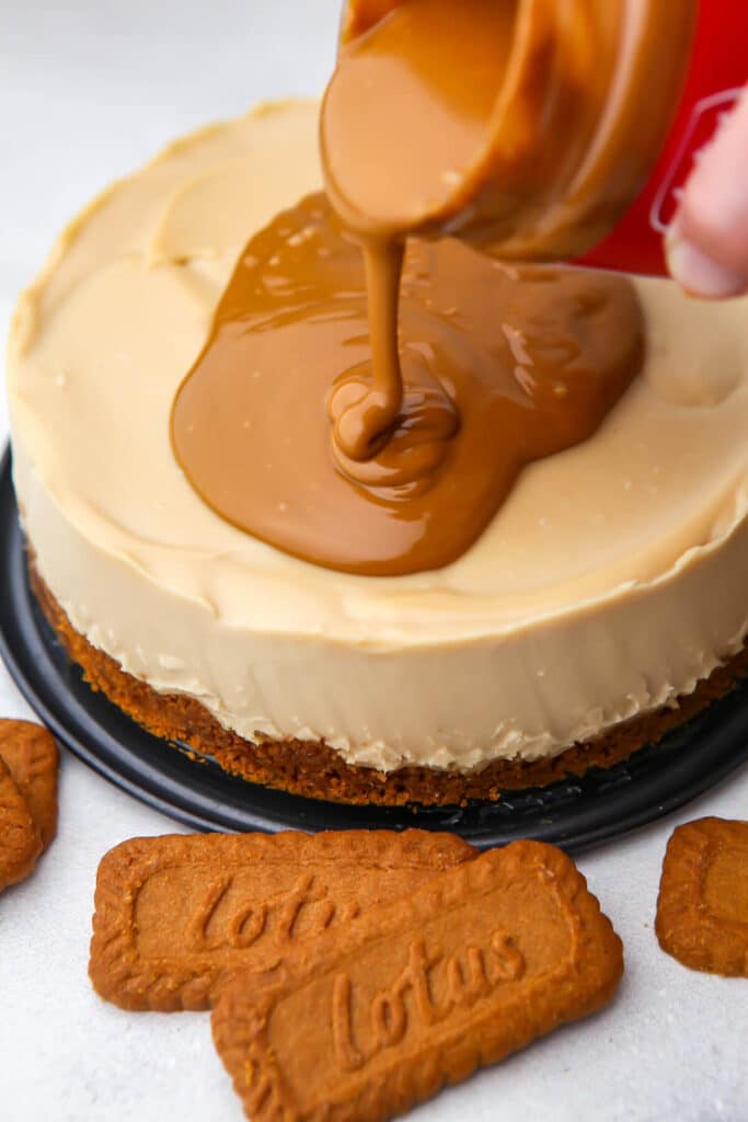 Pouring warm cookie butter over the top of a biscoff cheesecake.