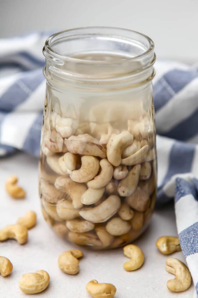 Raw cashews soaking in water in a mason jar.