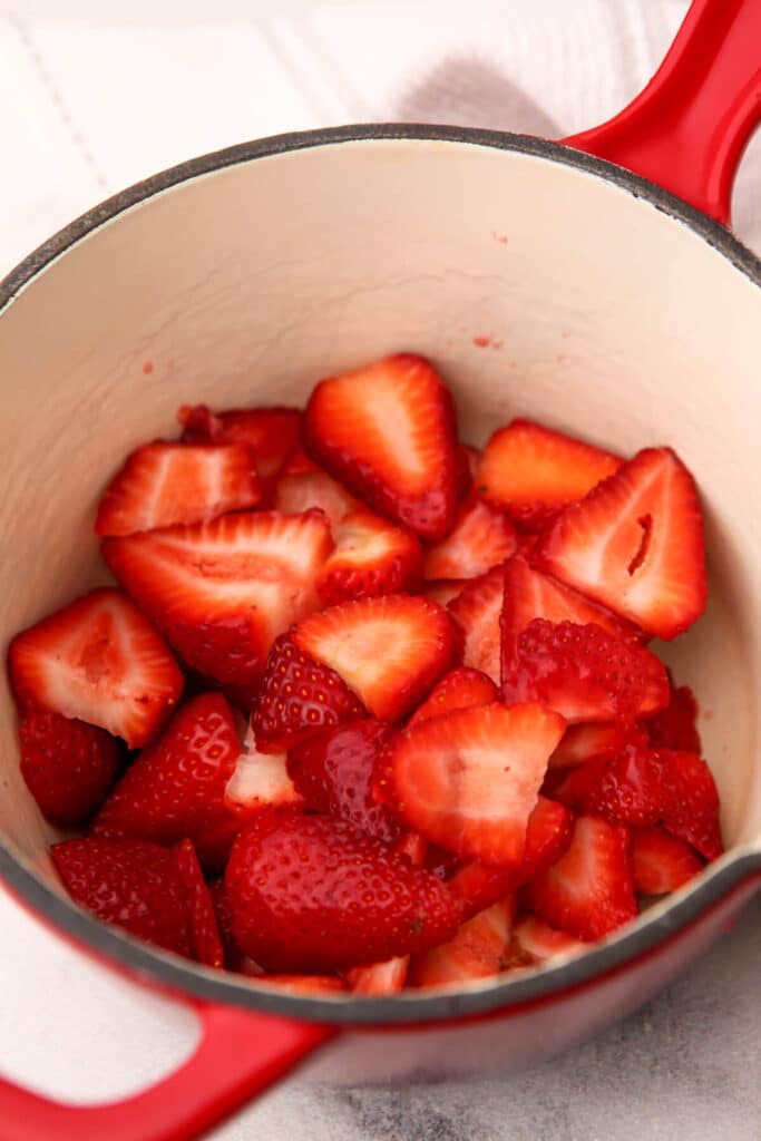 Cut strawberries in a red saucepan before cooking