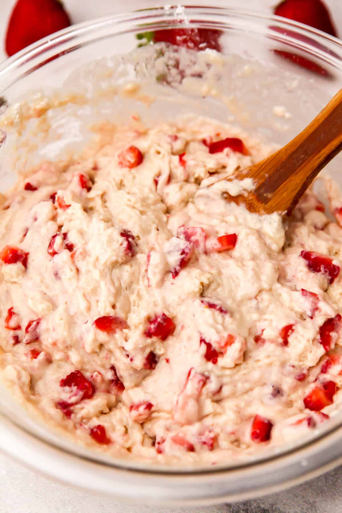 Stirring the strawberries into the muffin batter.