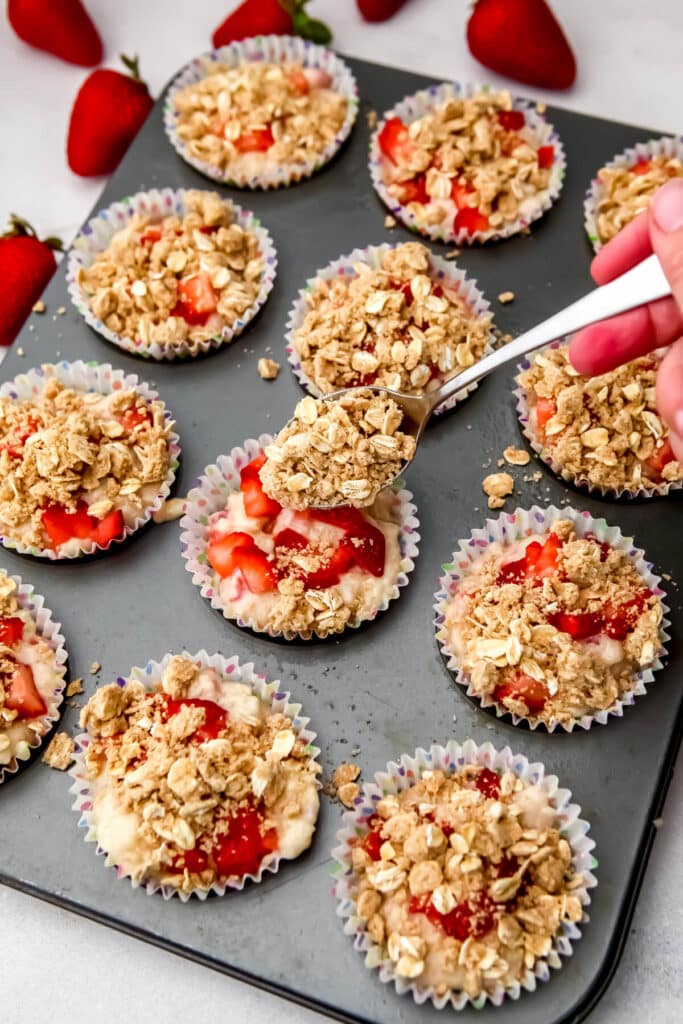 Adding strudel topping to strawberry muffins.