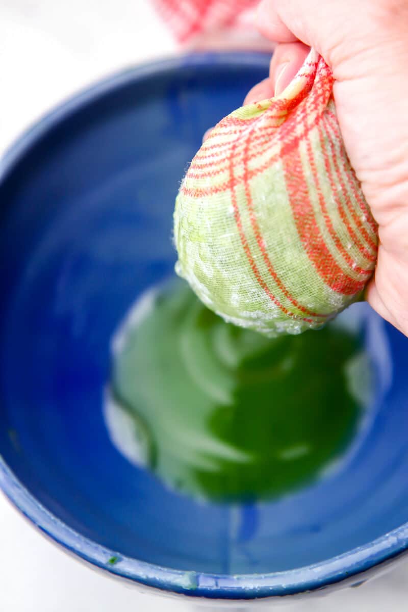 Squeezing out the liquid from shredded cucumbers with a tea towel.