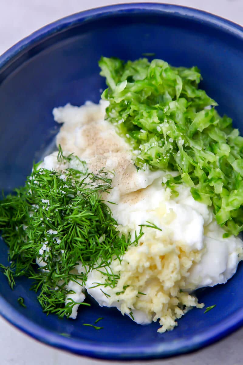 Vegan tzatziki sauce ingredients in a blue bowl before mixing.
