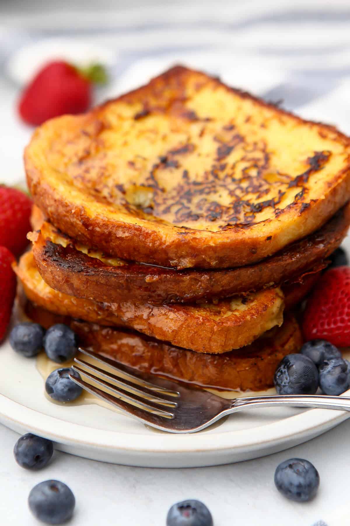 A stack of vegan French toast on a white plate with berries on the side made with Just Egg.