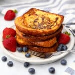 A stack of Just Egg French toast with maple syrup on top and berries around it.