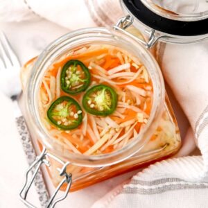 A top view of a jar full of pickled carrots and daikon.