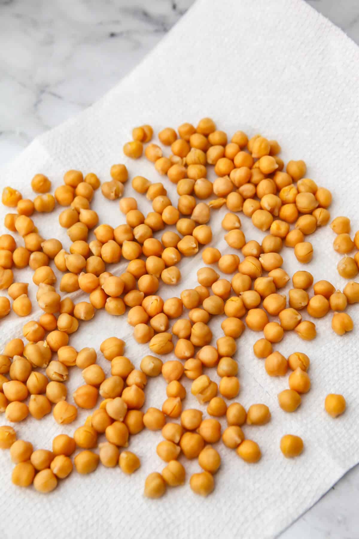 Drained and rinsed chickpeas drying on a paper towel.