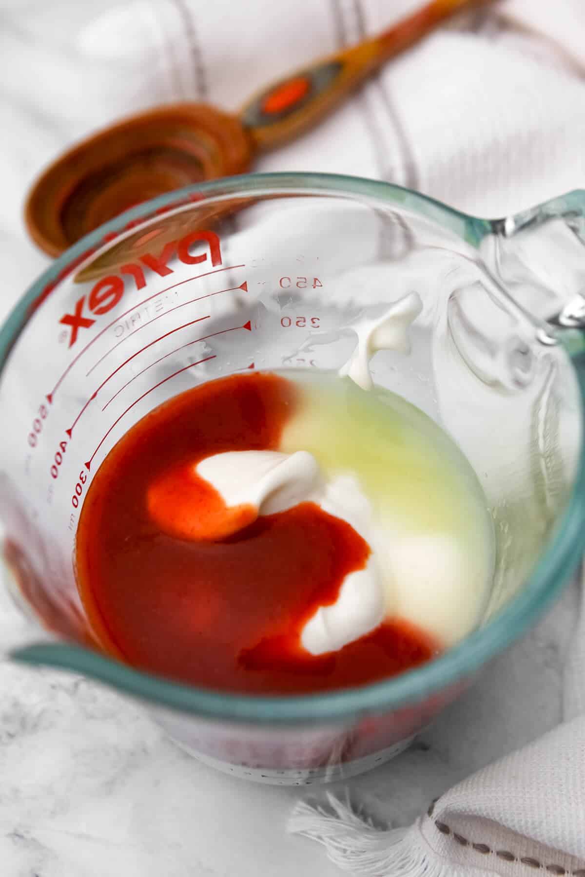 Vegan mayo, sriracha, and lime juice in a glass measuring container.