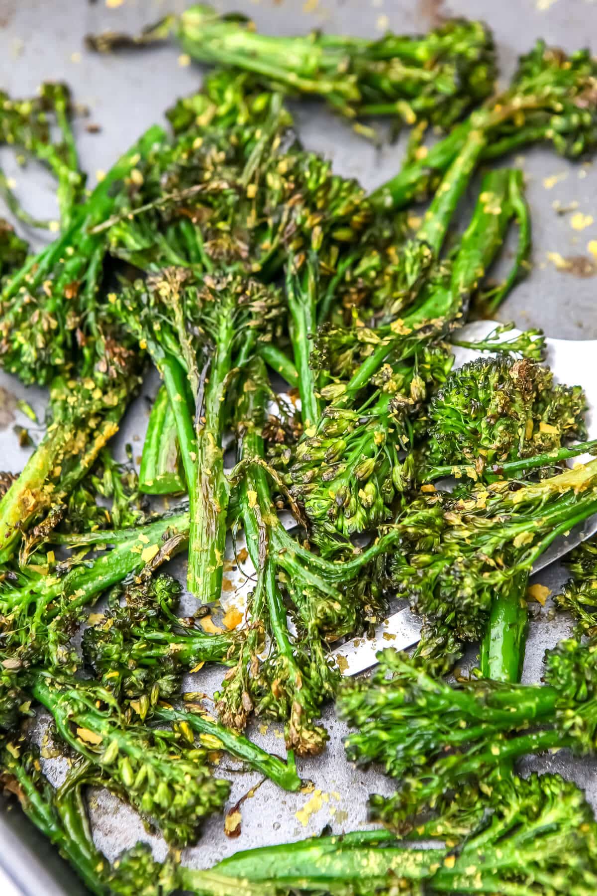 A close up of oven roasted tenderstem broccoli on a sheet pan.