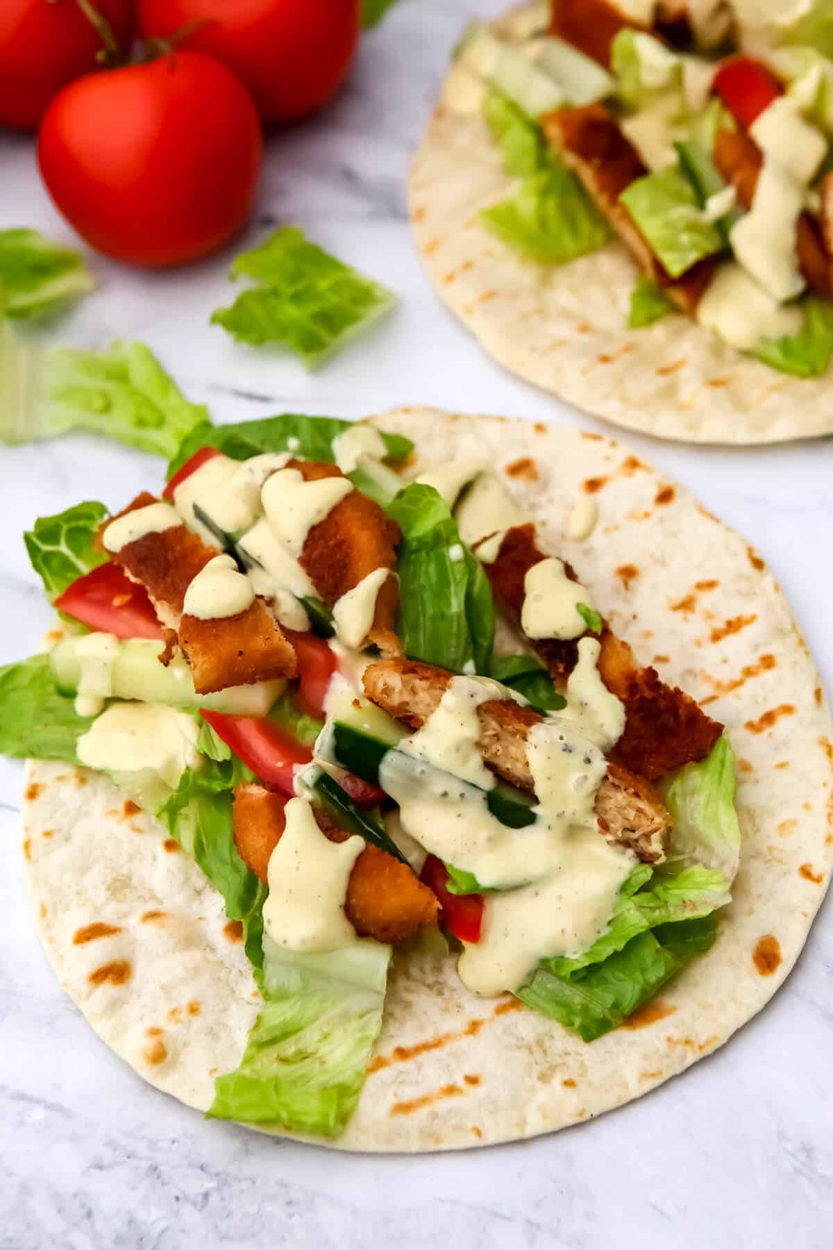 Vegan chicken wrap ingredients on a tortilla before wrapping it up.