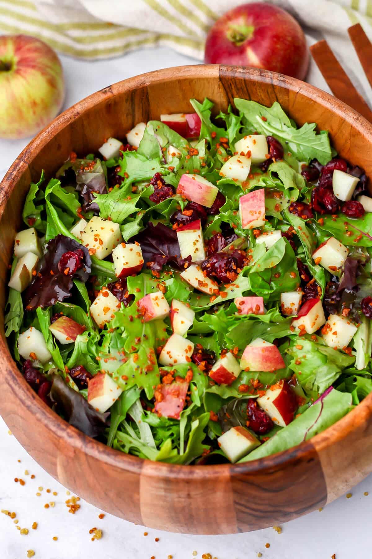 A top view of an apple salad made with mixed greens, diced apples and dried cranberries.