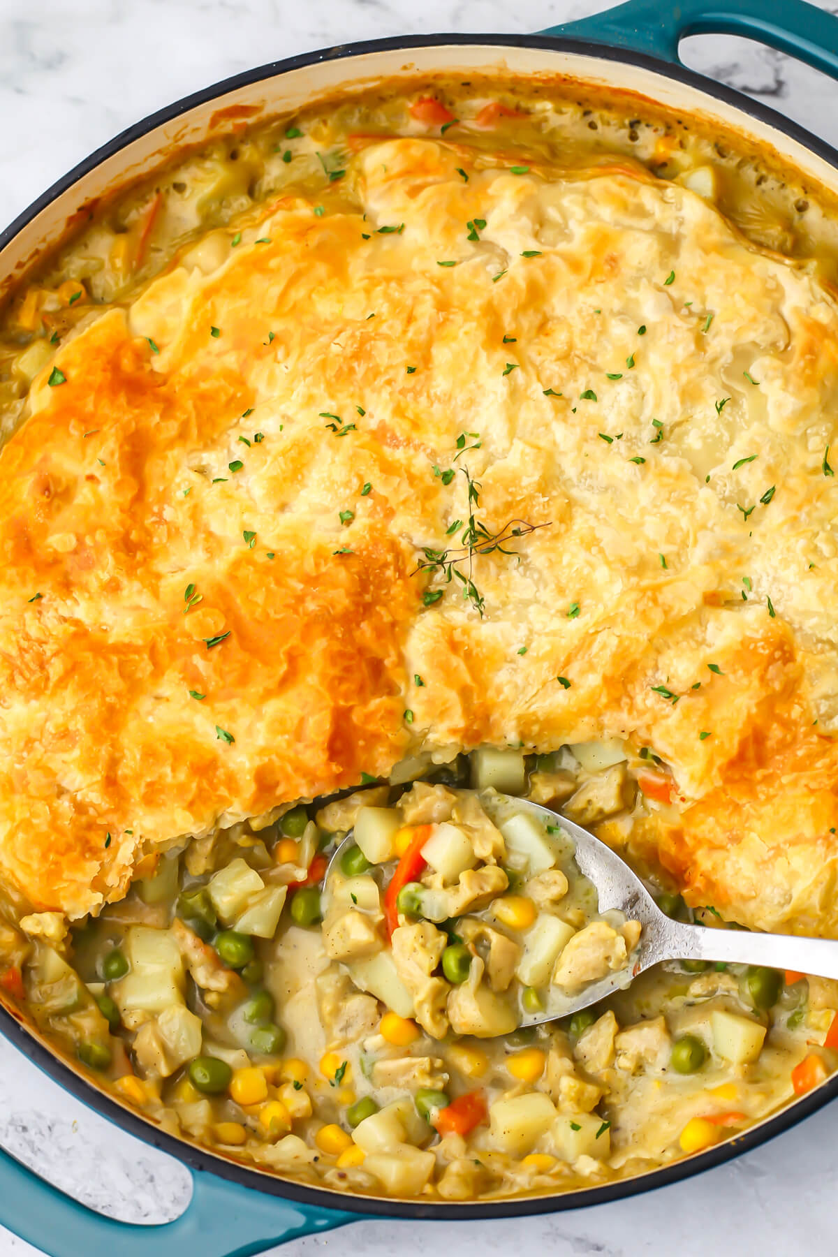 A top view of a vegan pot pie made in a large blue skillet and topped with puff pastry.