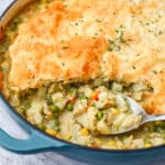 A vegan chicken pot pie made in a skillet with a pastry puff top with a spoon in it.