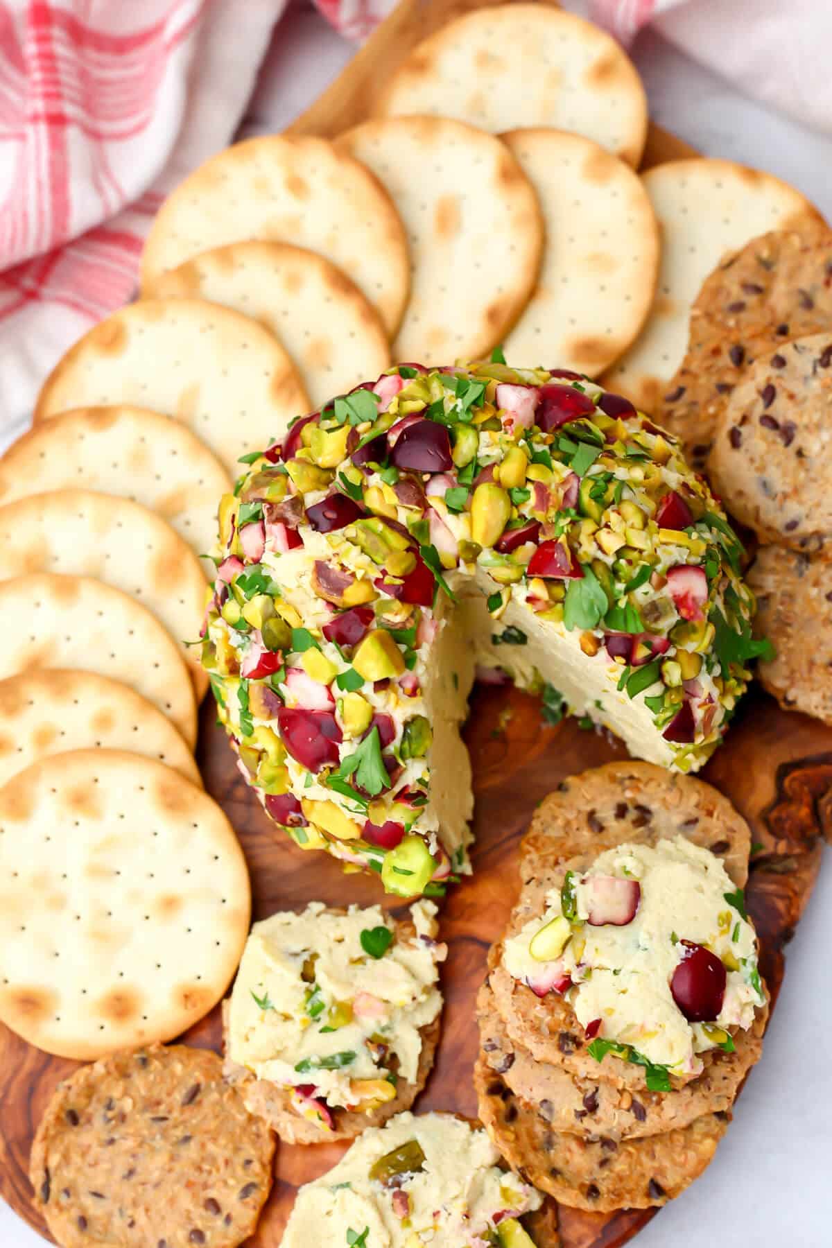 A top view of a tofu cheese ball with herbs served with crackers.