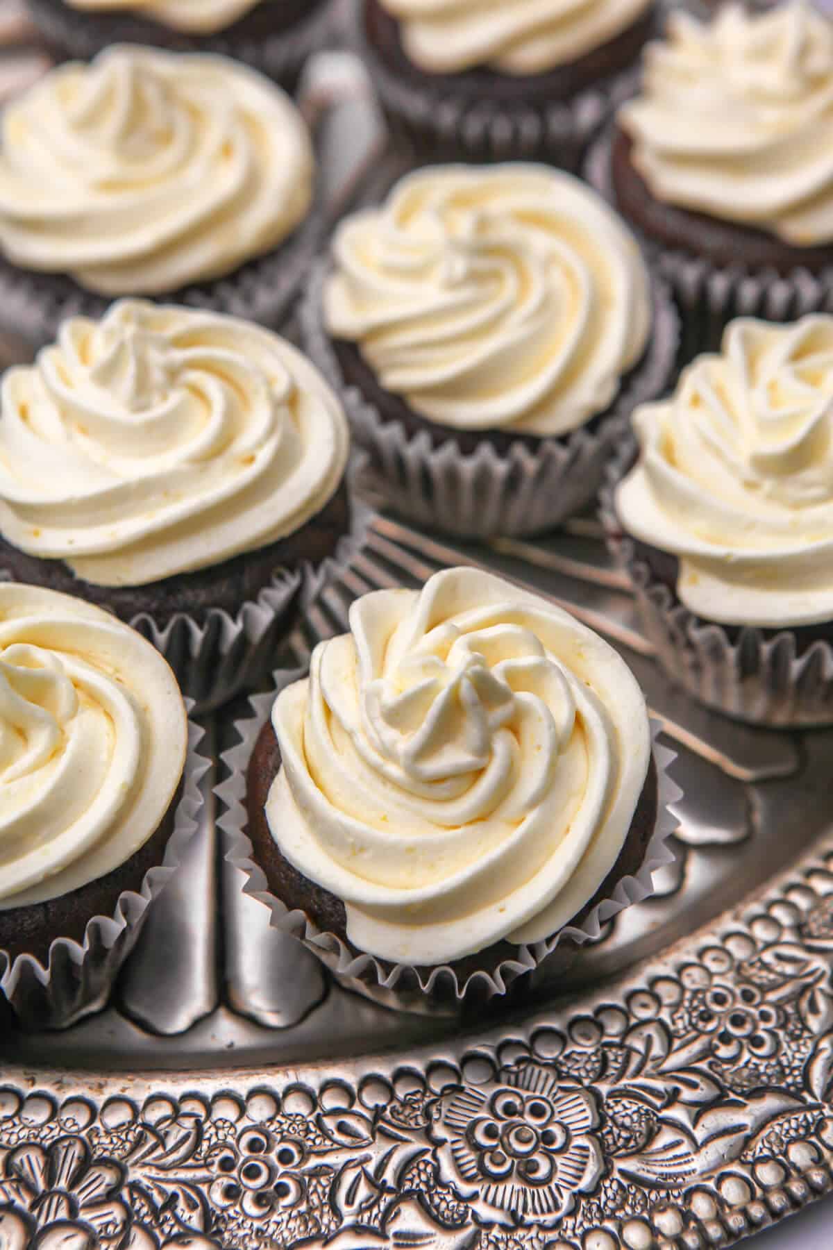 Vegan gingerbread cupcakes with lemon frosting on a silver serving tray.