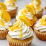 Vegan lemon frosting on lemon cupcakes with lemon wedge on top.