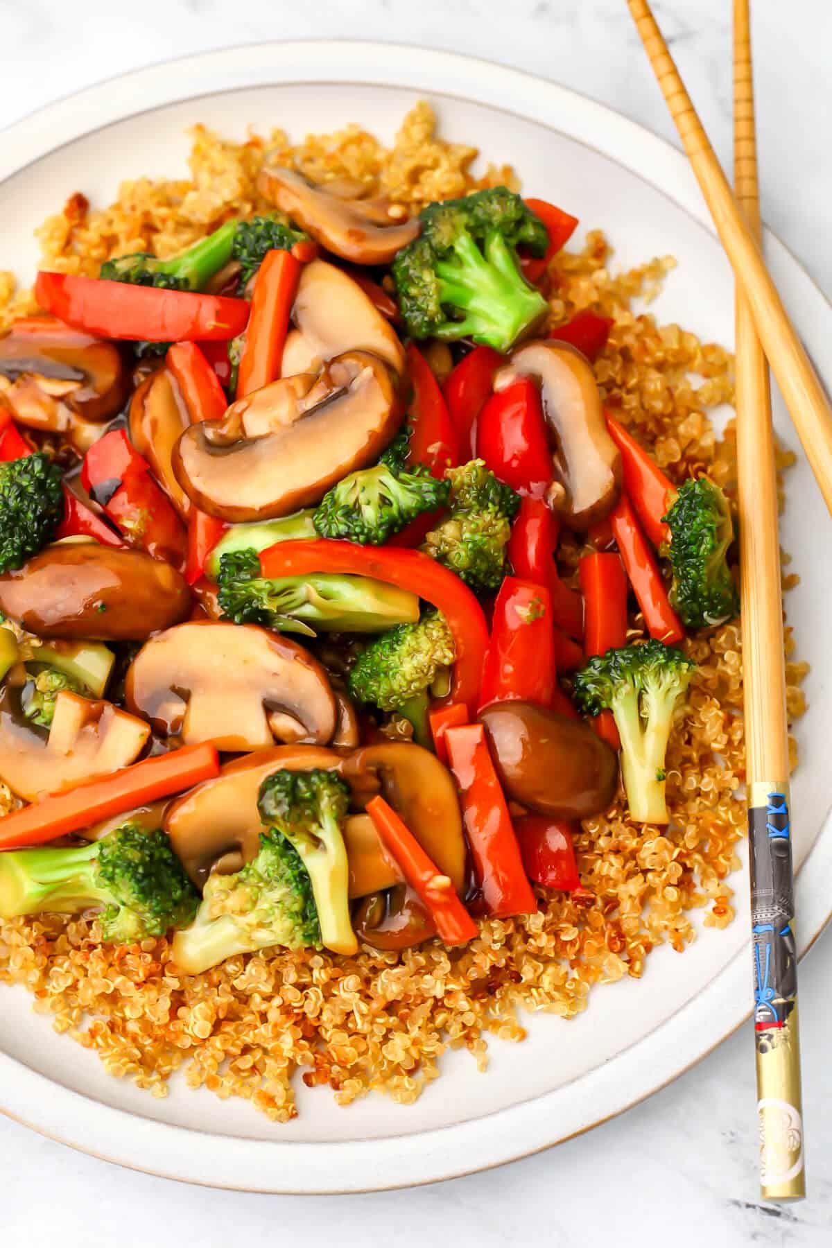 Simple vegetable stir-fry served over quinoa with chop sticks on the side.