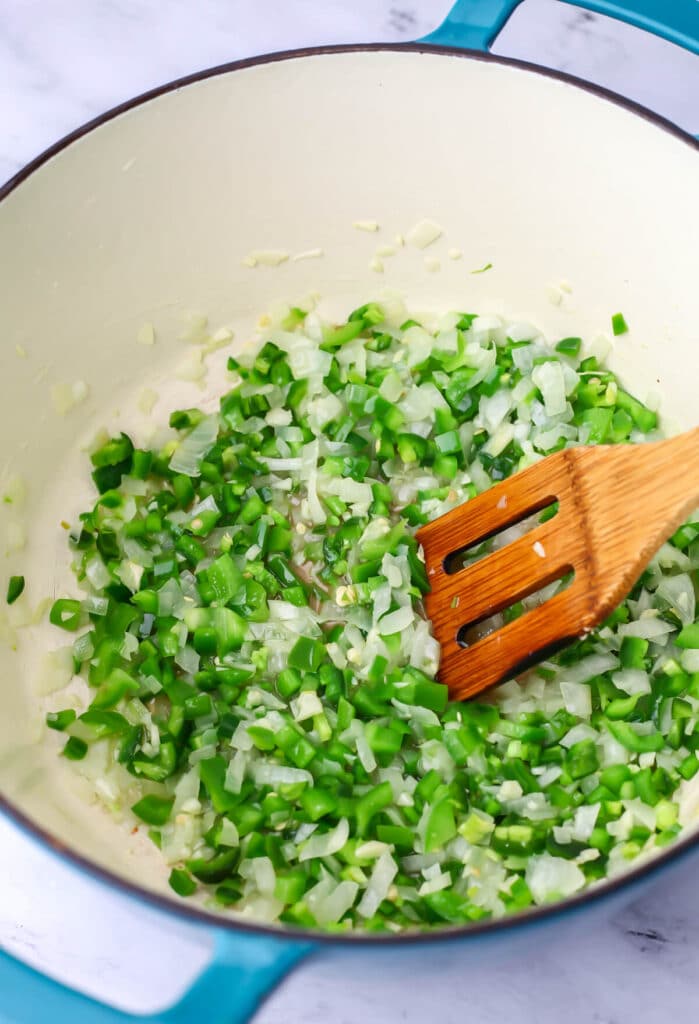 Onions, garlic, green peppers, and jalapenos cooking in a pot to make vegan chili.