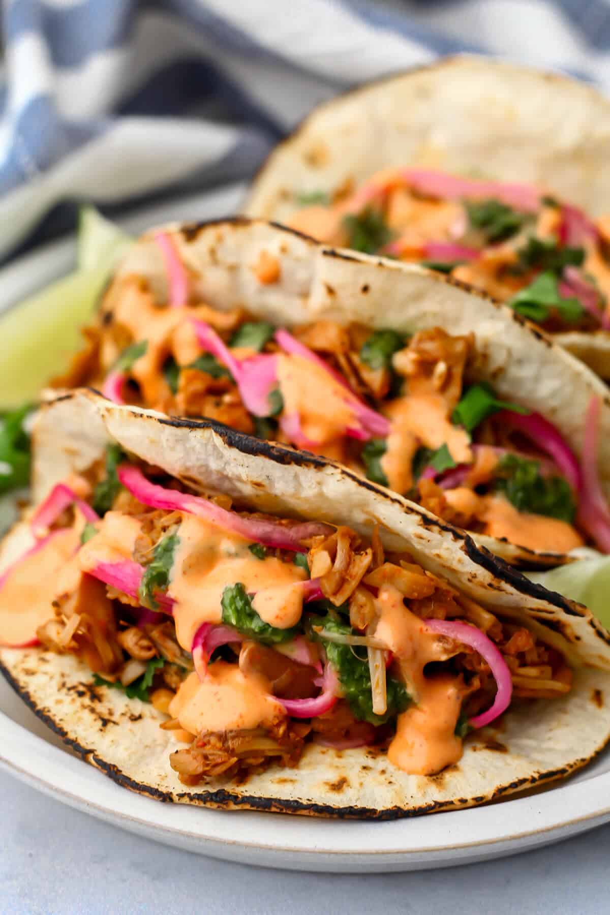Jackfruit tacos with pickled onions and vegan sriracha mayo drizzled on top.