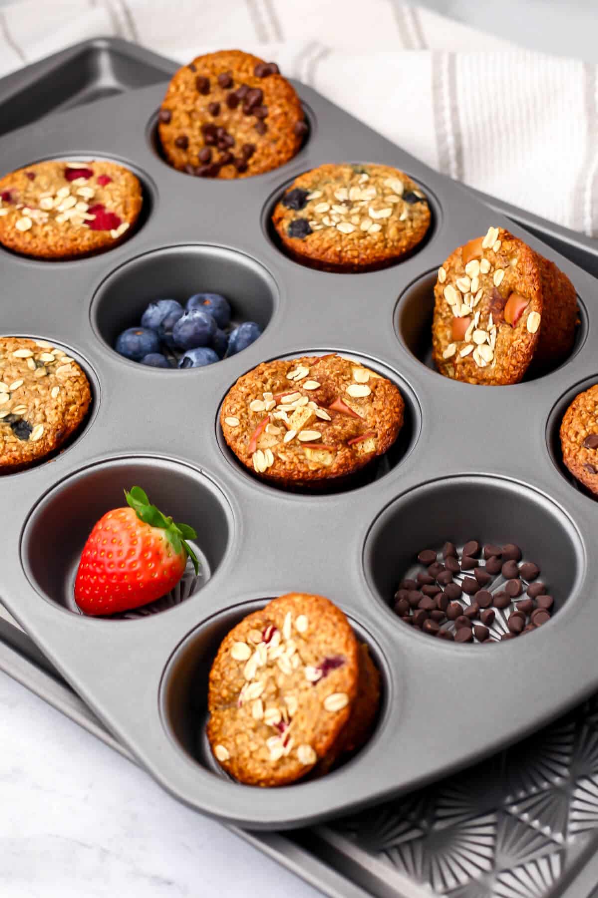 Vegan baked oatmeal cups in a variety of flavor in a muffin tin.