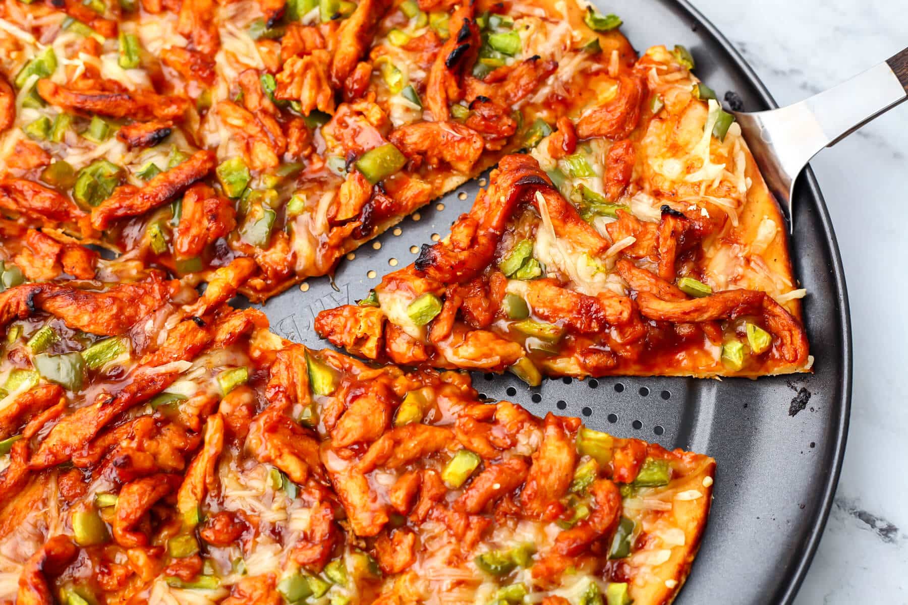 A vegan BBQ pizza with vegan chicken made from soy curls and green peppers on top.