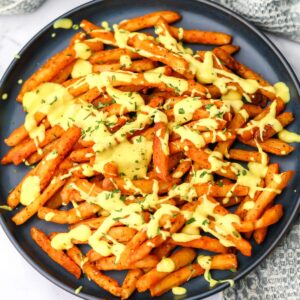 A blue plate filled with vegan cheese fries.
