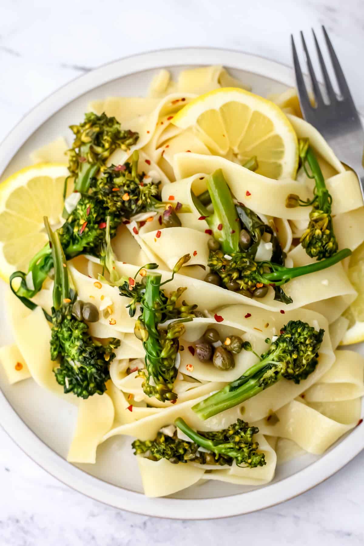 A top view of a plate filled with broccolini pasta with lemon and capers.