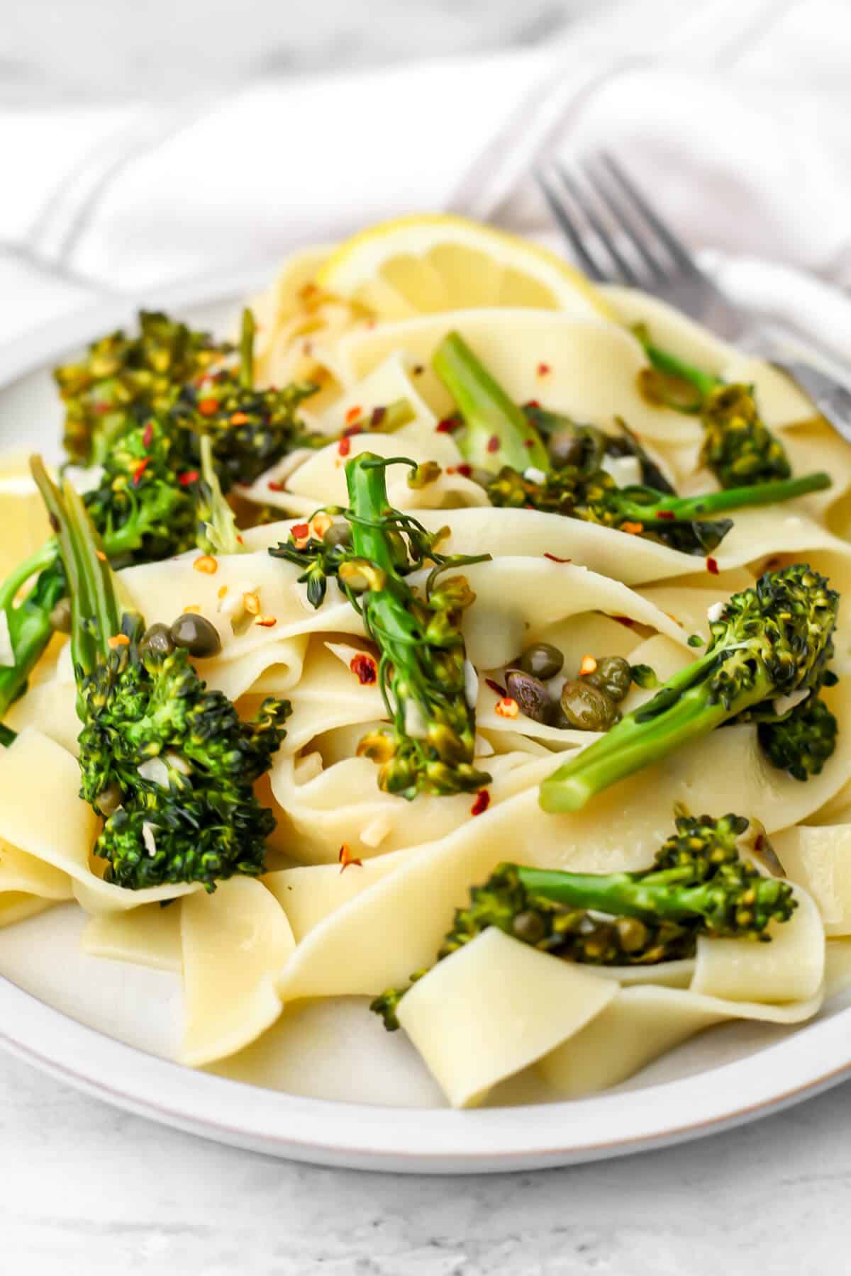 A plate full of broccolini pasta with a vegan lemon butter sauce with garlic and capers.