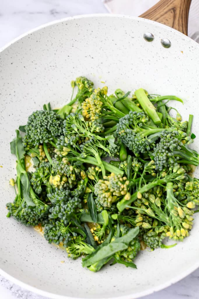 Broccolini in a white wok before it has been cooked.