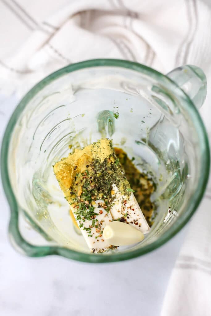 Silken tofu, herbs, nutritional yeast, and spices in a blender.