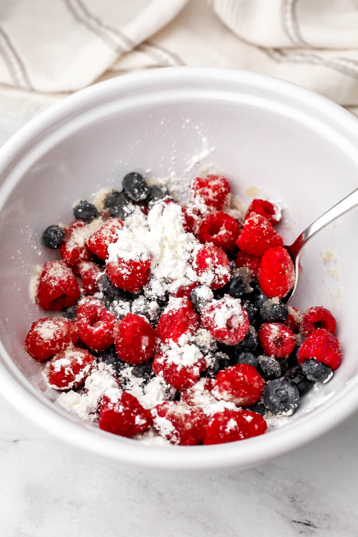 A bowl filled with berries, sugar, and cornstarch to make berry crumble.