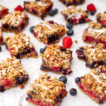 Vegan berry crumble bars made with blueberries and raspberries with an oat crumble topping with berries around them.