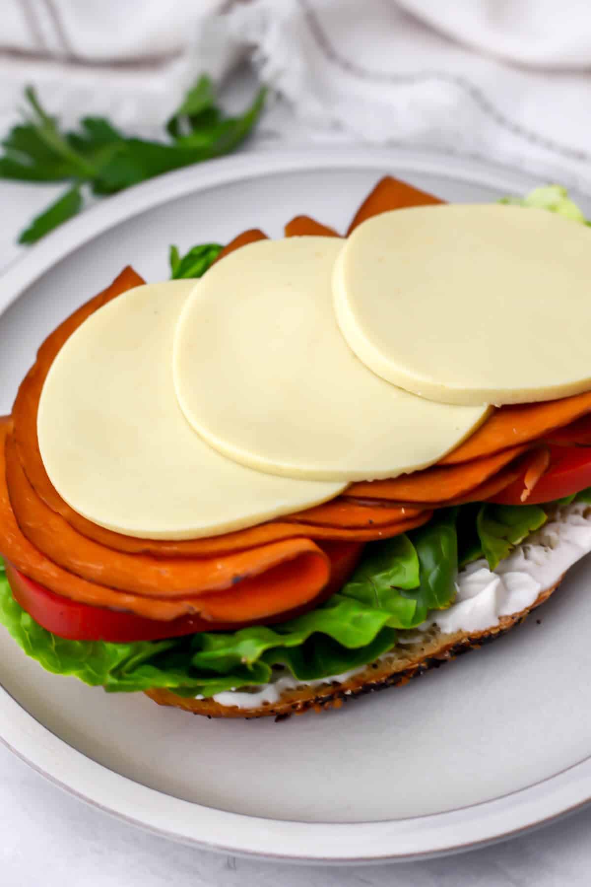 An open faced sandwich with vegan cheese slices on top.