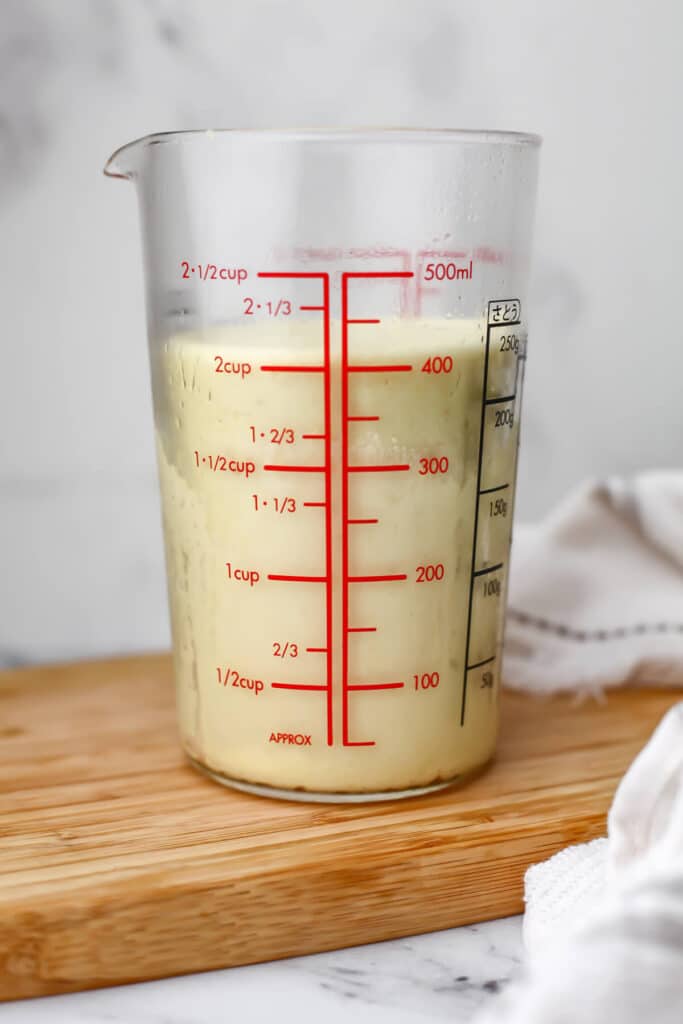 A tall glass cylinder with homemade vegan cheese to set for round slices.