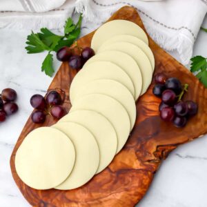 Vegan mozzarella slices on a cutting board with grapes around it.