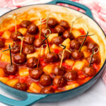 A blue skillet full of vegan sweet and sour meatballs with pineapple and red bell peppers.