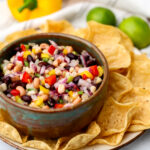 A bowl of vegan cowboy caviar with chips around it.