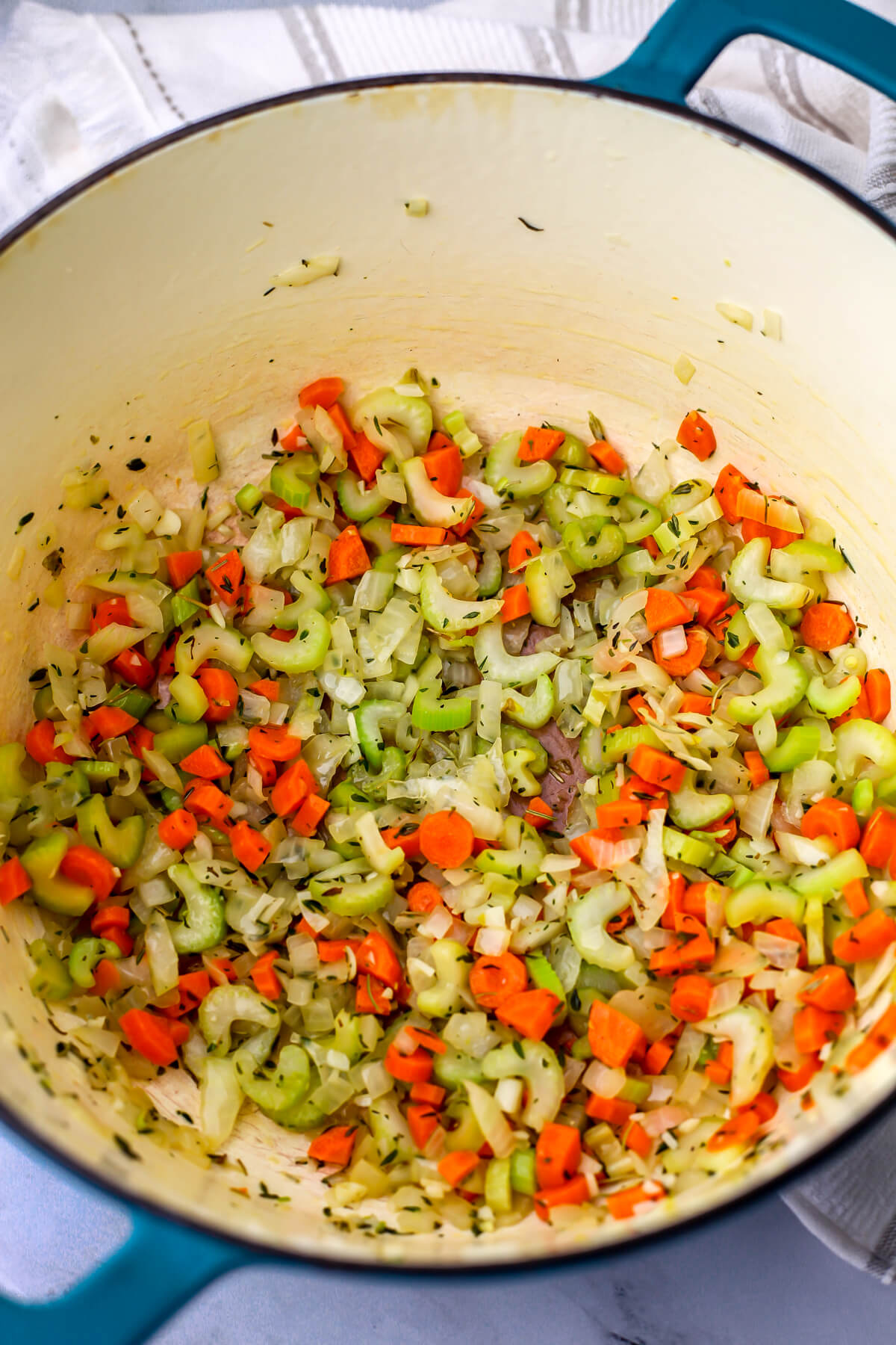 Onions, garlic, carrots, celery, and herbs in a soup pot to make barely soup.