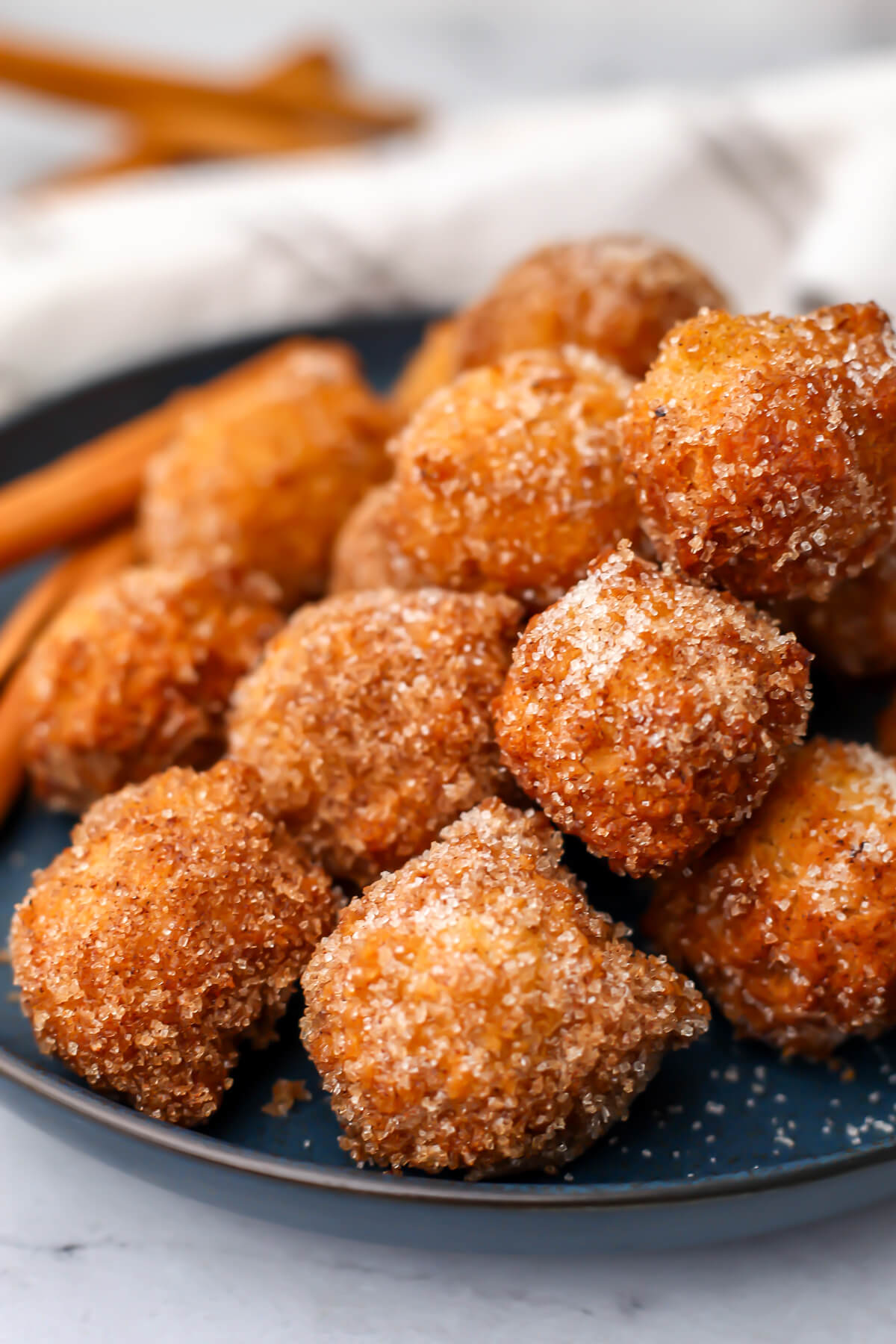 A close up of a plate filled with vegan cinnamon and sugar donut holes.